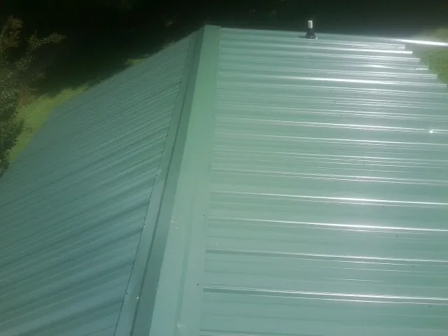 New green metal panels meeting at the ridge of a roof — Flat Roof Repair work by our crew in Hereford