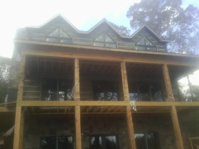 Dormers and porch framing on a large log home under construction — Roof Coating work by our crew in Hereford