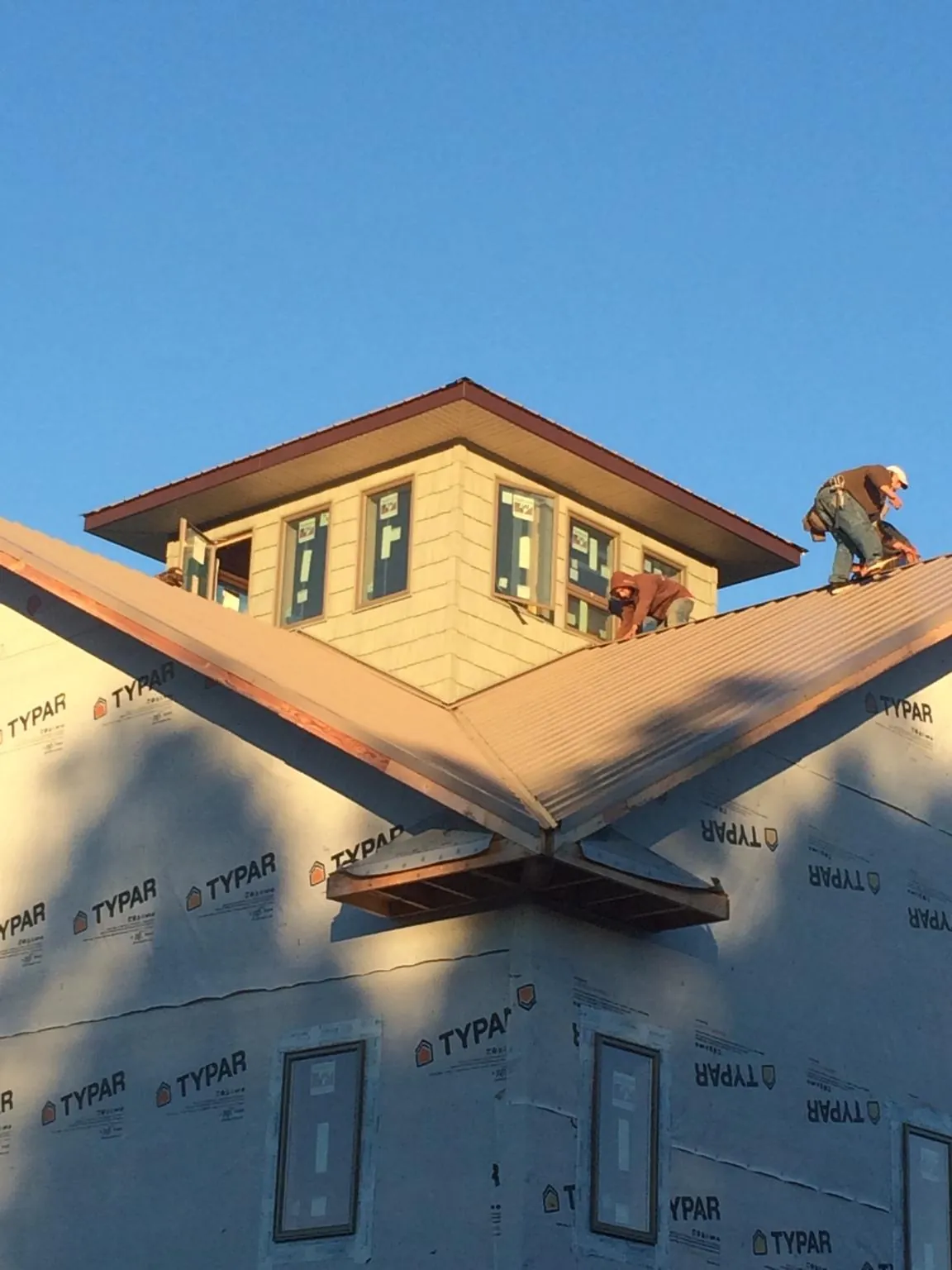 Roofers working around a rooftop cupola on a new metal roof at sunset — Roof Waterproofing in Hereford by Roofing Brothers
